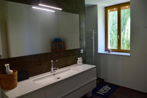 ein Badezimmer mit einem Waschbecken und einem großen Spiegel in der Unterkunft Spacious apartment in old farm close to Lac de Vouglans in La Tour-du-Meix