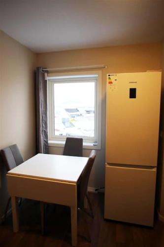 a kitchen with a table and a refrigerator and a window at Sentral leilighet med 3 soverom 2etg in Harstad