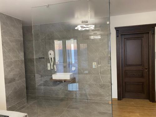 a bathroom with a shower with a sink and a mirror at Едем in Brzezhany