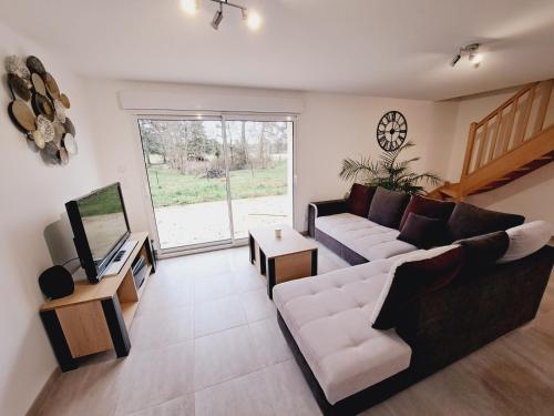 a living room with a couch and a tv at Le Bonheur est dans le Pré. in Saint-Romain-sur-Cher