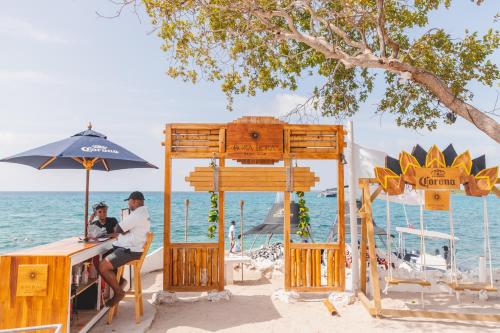 zwei Personen sitzen an einem Tisch am Strand in der Unterkunft Bora Bora Beach Club & Hotel in Isla Grande