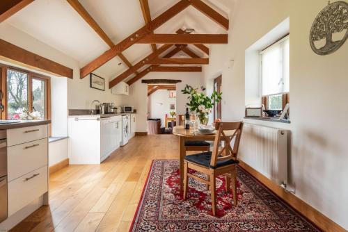 a kitchen with a table and a dining room at Linhay at East Trenean Farm -Luxury retreat for 2 with stunning rural views, private hot tub and EV charging in Looe