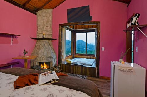 una camera da letto con parete rosa e camino di Pousada Lua de Minas a Visconde De Maua