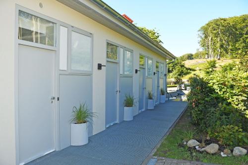 a white building with doors and potted plants on the sidewalk at schöne Ferienwohnungen mit Kamin im Ostseebad Sellin Kopie in Ostseebad Sellin