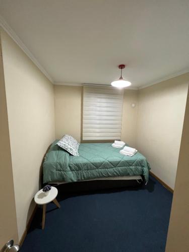 Habitación pequeña con cama verde y mesa. en Arriendo departamento, en Temuco