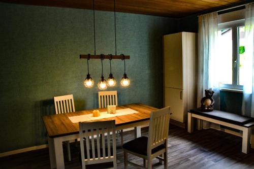 a dining room with a table with chairs and lights at Ferienwohnung Jungbär - Die Wohlfühl-Adresse im Stangenwald in Sankt Ingbert