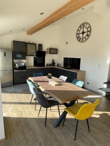 une cuisine avec une table et des chaises et une horloge au mur dans l'établissement Le loft, à Buhl-Lorraine