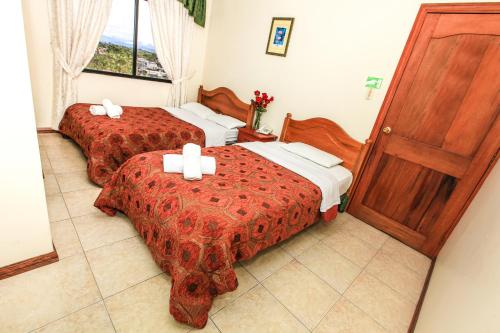 een hotelkamer met 2 bedden en een deur bij Hotel Colonial in Puyo