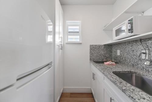 uma cozinha com armários brancos e um lavatório em The Mariner Suites #31 em Hollywood