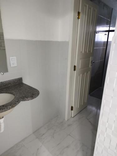 y baño blanco con lavabo y ducha. en Apartamento aconchegante, en Porto Seguro