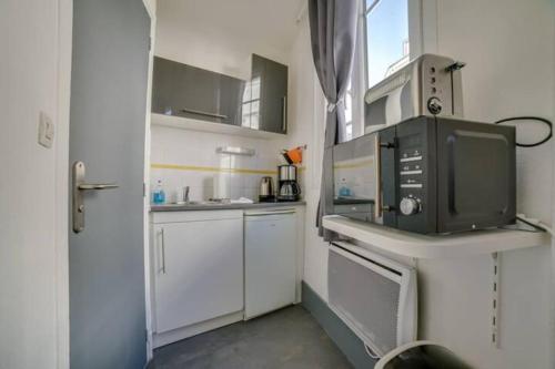 une petite cuisine avec des armoires blanches et un micro-ondes dans l'établissement La tête dans les nuages, à Rouen