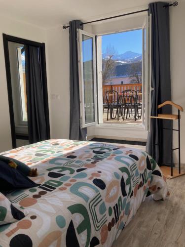 ein Schlafzimmer mit einem Bett und einem großen Fenster in der Unterkunft Le Gaudissart 2 in Barcelonnette