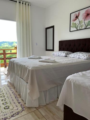 a bedroom with two beds with white sheets and a window at Chácara Jerusalém in Lindóia
