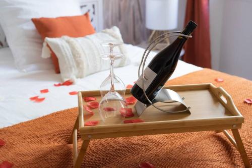 a bottle of wine and a hourglass on a bed at Ode à l'amour : studio intimiste in Toulon