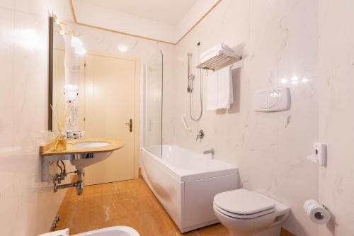 a white bathroom with a toilet and a sink at Hotel Alle Acque in Lonigo