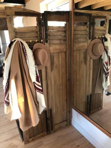 une chambre avec un miroir et des chapeaux sur un mur dans l'établissement Steen Home : Petite longère de charme, à Boeschèpe