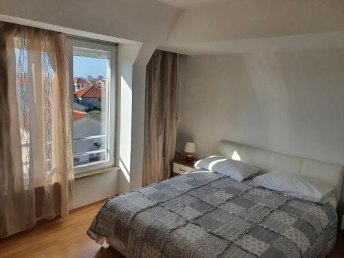 um quarto com uma cama e uma grande janela em Cozy Two-Bedroom Apartment em Zadar