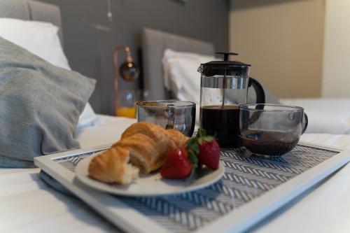 a plate of croissants and strawberries on a tray on a bed at Whitworth House, Sleeps 6 TVs in all bedrooms, WIFI - 3 bedroom in Northampton