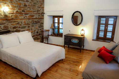 a bedroom with a bed and a couch and a mirror at Olympia Avra in Palaios Panteleimonas