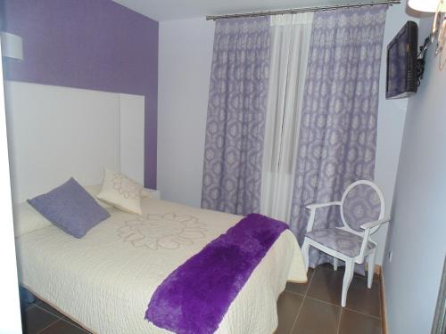 a bedroom with a bed with a purple blanket and a chair at Hotel Ribera de Langa in Langa de Duero