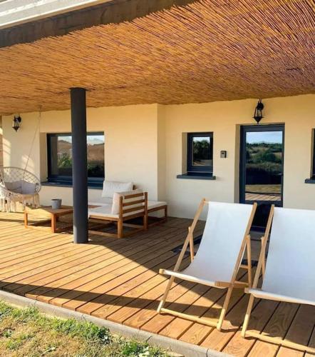 a wooden deck with chairs and tables and windows at L'ÉCHAPPÉE BRETONNE in Plouider