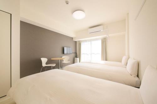 a bedroom with two beds and a table at Bay Hotel Urayasu-ekimae in Urayasu
