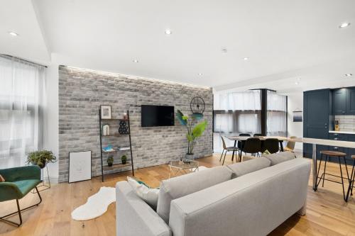 a living room with a couch and a brick wall at Hounds Gate Luxury Apartments by 1508 Stays in Nottingham