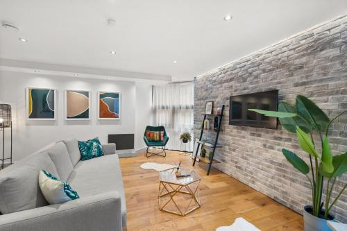 a living room with a gray couch and a brick wall at Hounds Gate Luxury Apartments by 1508 Stays in Nottingham