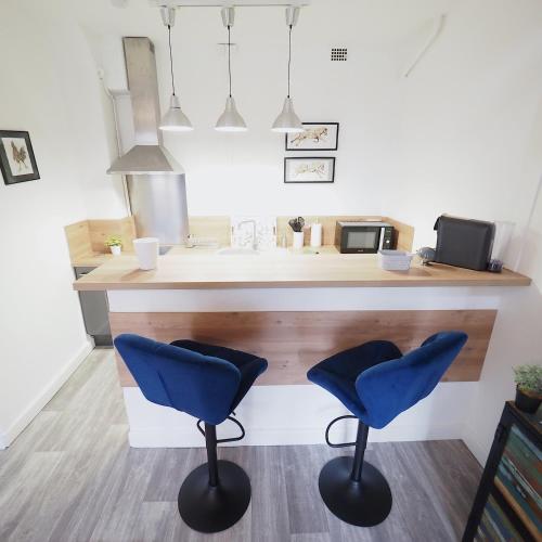 une cuisine avec deux chaises bleues à un comptoir dans l'établissement LE PLAISANCE - Face au Parc - Duplex - Balcon, à Vichy