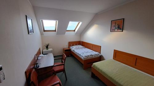Habitación pequeña con 2 camas, escritorio y sillas. en Penzion Aida Ostrava, en Ostrava