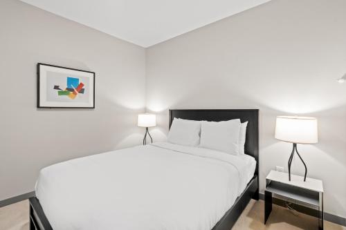 a white bedroom with a bed and two lamps at WhyHotel by Placemakr, Columbia in Columbia