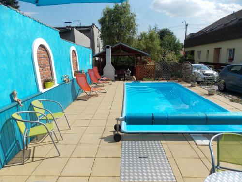 a swimming pool with chairs and a blue building at Penzion Aida Ostrava in Ostrava