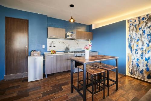 cocina con paredes azules, mesa y nevera en Loft Roma Norte en Ciudad de México
