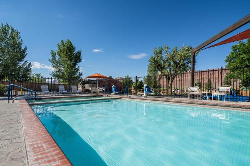 a swimming pool at a resort with tables and chairs at Sun Outdoors Arches Gateway in Moab