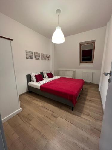 a bedroom with a large bed with a red blanket at Apartamenty Przy Rynku Trzebnica in Trzebnica