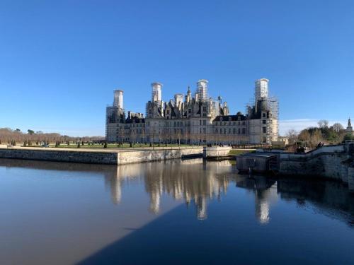 a large castle sitting next to a body of water at La petite Chambord aux portes du château in Mont-près-Chambord
