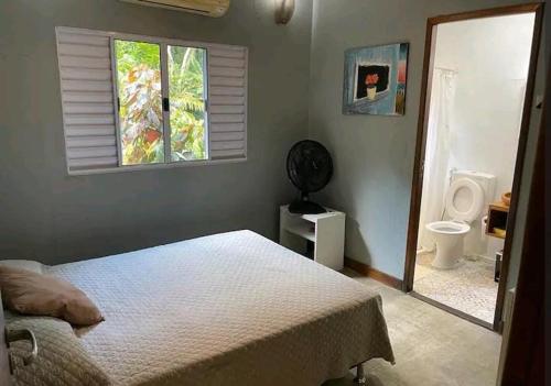 a bedroom with a bed and a bathroom with a toilet at Sítio Vale Das Flores in Maricá