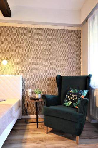 a bedroom with a green chair next to a bed at Zajazd Stodoła sauna w cenie in Stronie Śląskie
