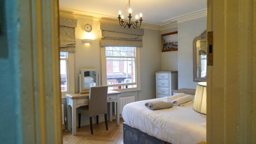 Schlafzimmer mit einem Bett, einem Schreibtisch und einem Tisch in der Unterkunft 4 Bedroom Residence Hammersmith Fulham in London