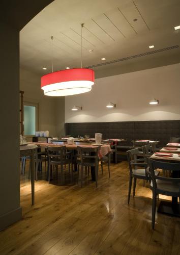 フィレンツェにあるHotel Rosso23 - WTB Hotelsのテーブルと椅子とシャンデリアのあるダイニングルーム