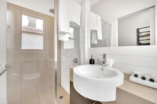 a white bathroom with a sink and a shower at Grosvenor 3121 Richmond in Melbourne