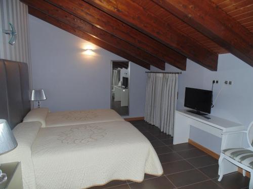 a bedroom with two beds and a desk and a television at Hotel Ribera de Langa in Langa de Duero