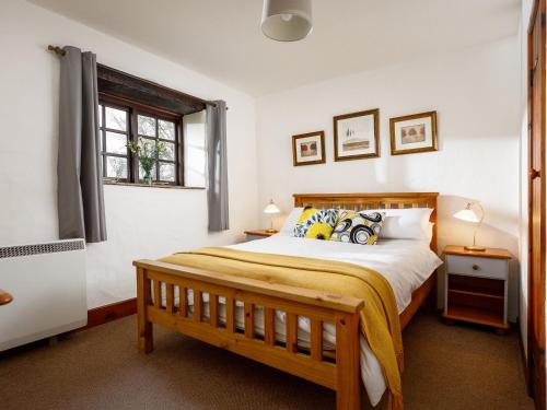 a bedroom with a wooden bed and a window at Ash Cottage in Launceston
