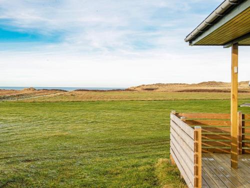 a house with a wooden fence in a field at 6 person holiday home in Lemvig in Trans