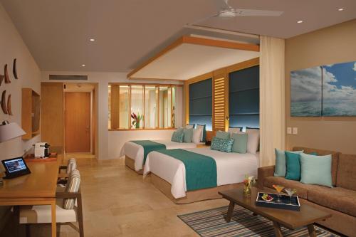 a hotel room with two beds and a couch at Dreams Playa Mujeres Golf & Spa Resort - All Inclusive in Cancún