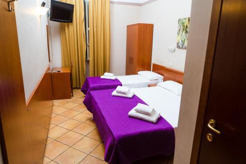 2 camas en una habitación con sábanas y toallas púrpuras en Hotel Cervia en Roma