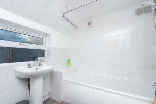 a white bathroom with a sink and a bath tub at Central Townhouse Wolverhampton - Sleeps 8 - Ideal for Contractors & Families in Wolverhampton