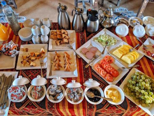a table with many plates of food on it at Relaxing Desert Camp in Merzouga