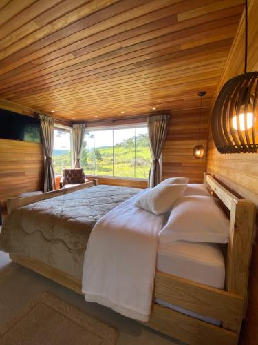 um quarto com uma cama grande e um tecto em madeira em Chalé do Lago Urupema SC em Urupema