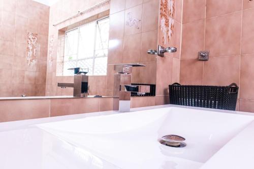 a bathroom with a white tub and a shower at CHIC Guest House & Solar system accommodations in Germiston